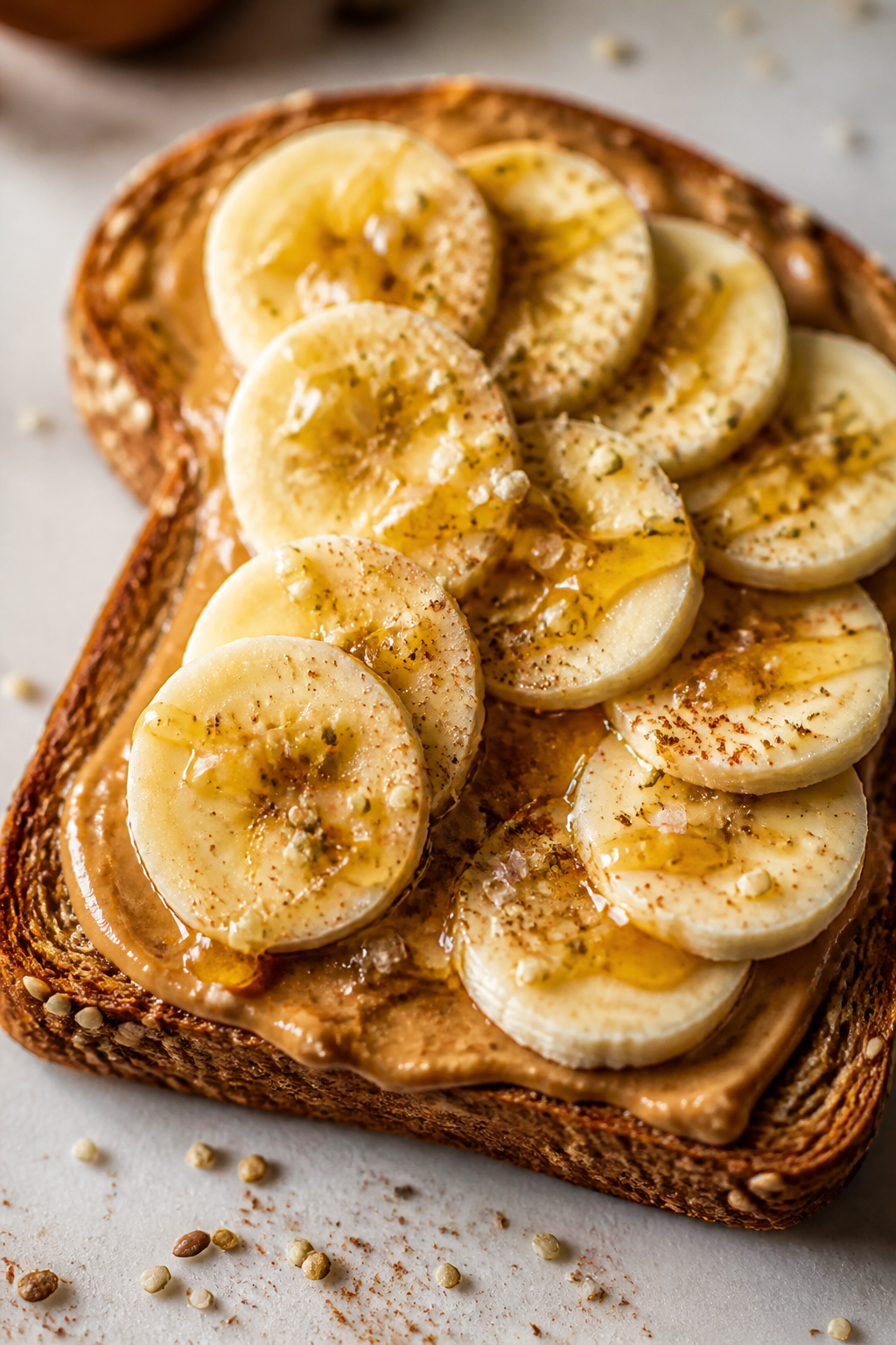 Close-up detail of freshly assembled peanut butter banana toast: thick swirl of natural peanut butte