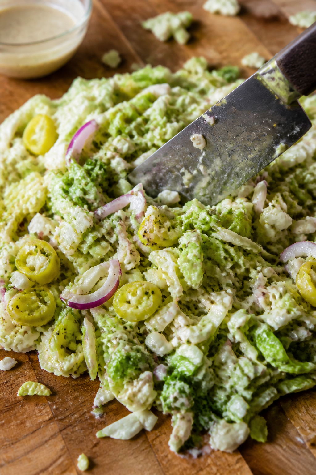 Close-up detail, process shot: The chopped Italian grinder salad being mixed and chopped on a large