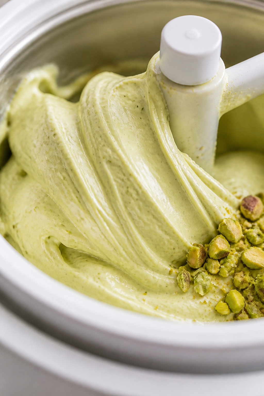 Close-up detail shot of freshly churned pistachio ice cream in the ice cream maker, thick and soft-s