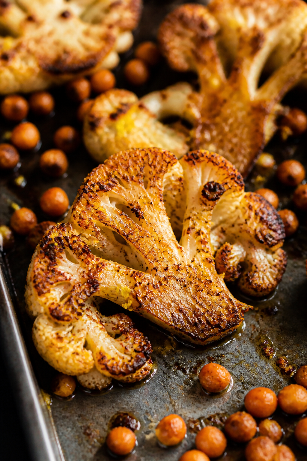 Close-up detail shot of oven-roasted cauliflower just after flipping: deeply golden slabs and floret
