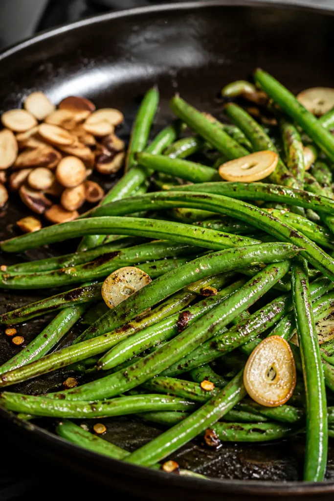 Cooking process, close-up detail: Sizzling stir-fried green beans in a dark carbon-steel skillet, be