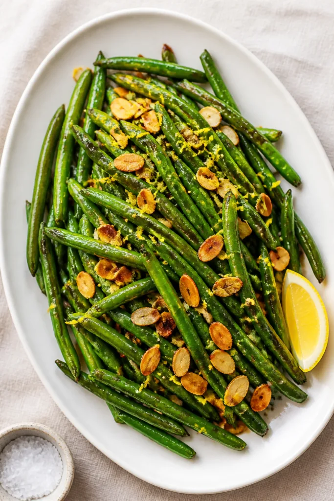Final dish, top view: Overhead shot of Stir-Fried Green Beans With Almonds plated on a wide, matte w
