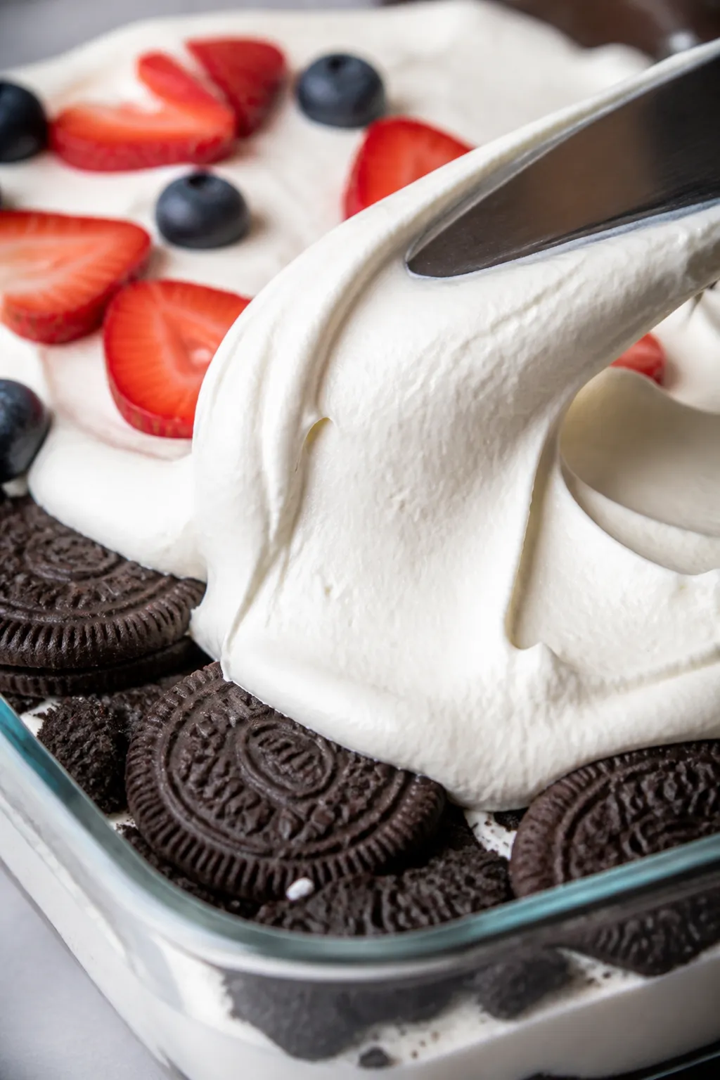Close-up process detail of the second layering step: a tight macro of a snug Oreo layer in the dish 