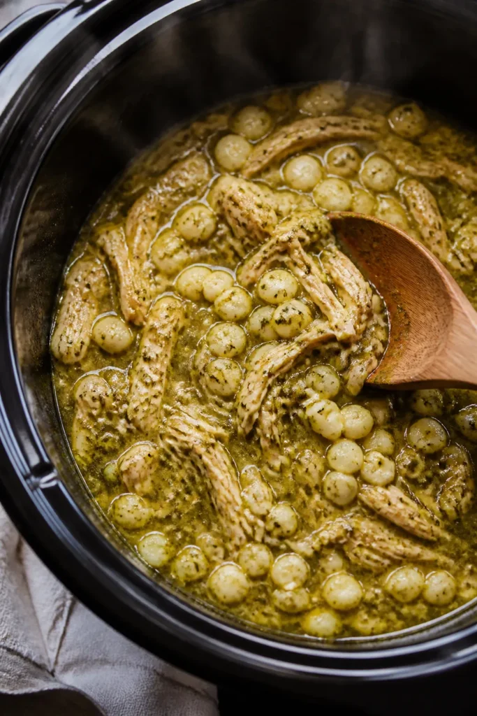 Cooking process, close-up detail: Crockpot chicken pozole verde mid-simmer, overhead shot of tender