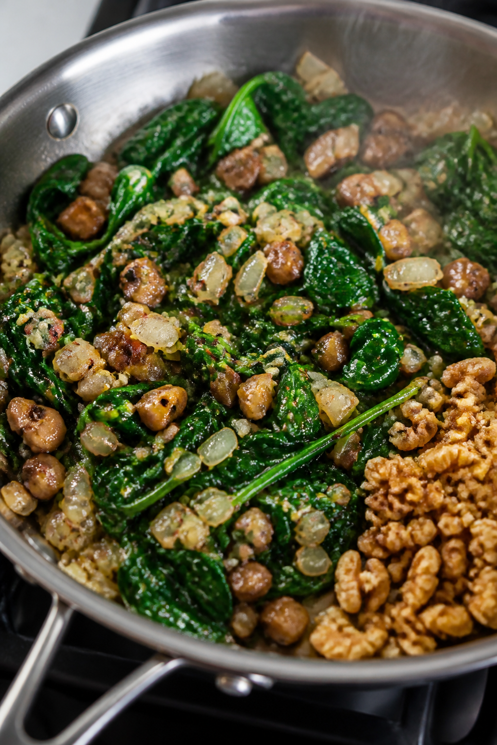 Cooking process close-up: Sautéed spinach, chopped mushroom stems, and onions mingling in a stainle