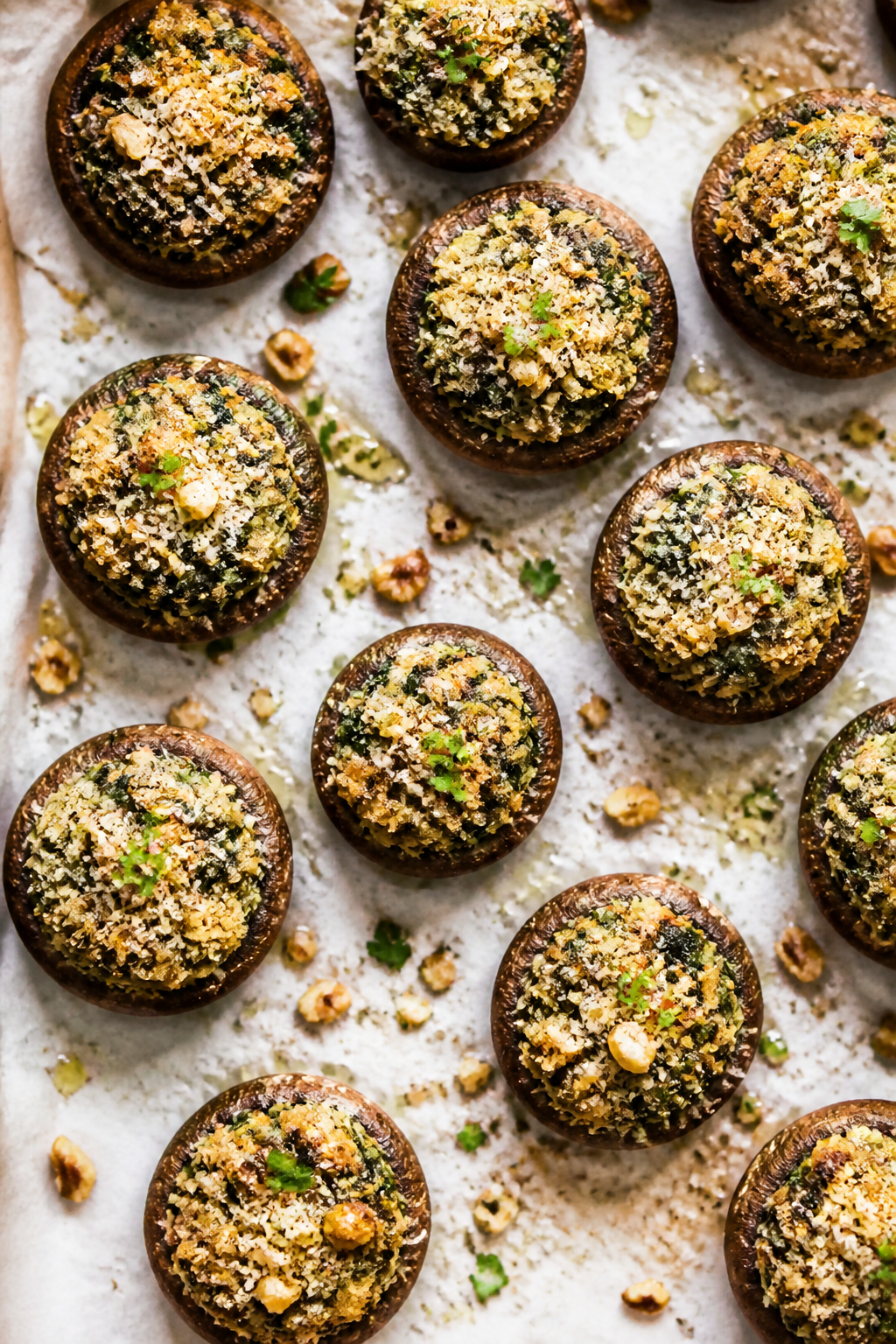 Final dish overhead: Baked stuffed cremini mushroom caps arranged on a parchment-lined sheet, mounde