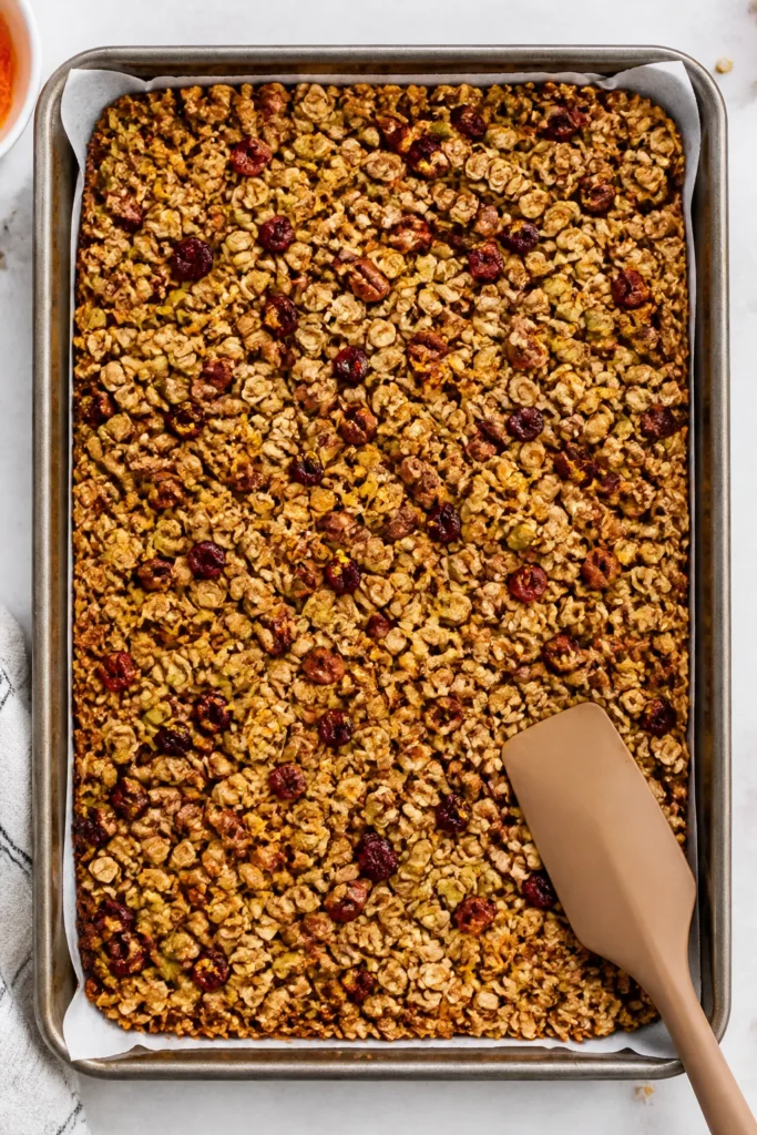 Overhead shot of freshly baked pumpkin and sunflower seed granola cooling on a parchment-lined sheet